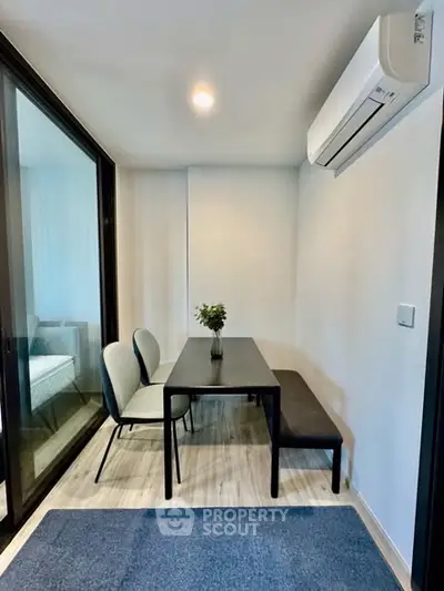 Modern dining area with sleek table and chairs, featuring a minimalist design and air conditioning.