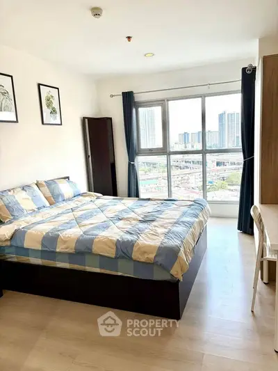 Bright bedroom with large window offering stunning city view and modern decor.