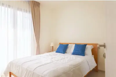 Cozy bedroom with natural light and modern decor, featuring a comfortable bed and stylish blue cushions.