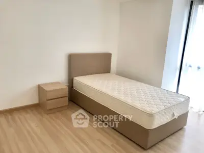 Minimalist bedroom with single bed and wooden nightstand, featuring natural light and modern design.