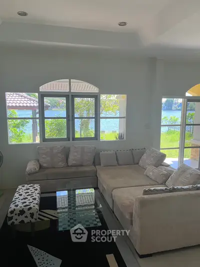 Spacious living room with cozy sectional sofa and stunning lake view through large windows.