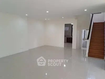 Spacious empty living room with glossy tile flooring and staircase, ideal for customization.