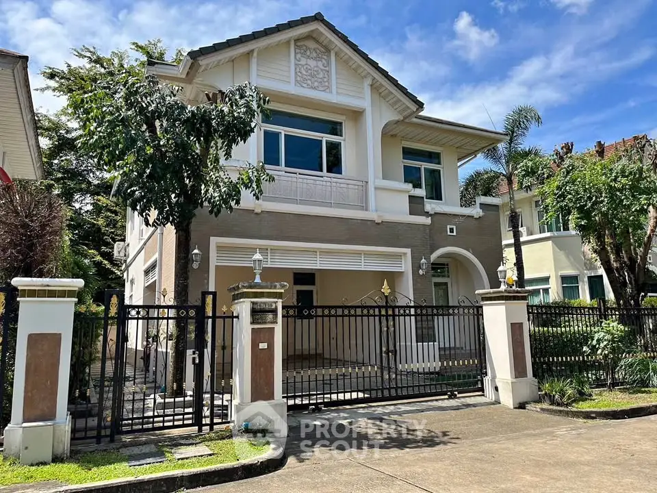 Elegant two-story house with gated entrance and lush greenery, perfect for family living.