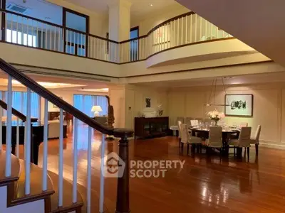 Luxurious open-plan living and dining area with elegant staircase and high ceilings.