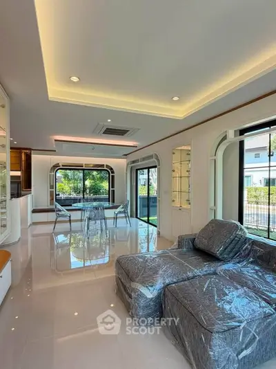 Luxurious modern living room with elegant decor and large windows offering natural light and garden view.