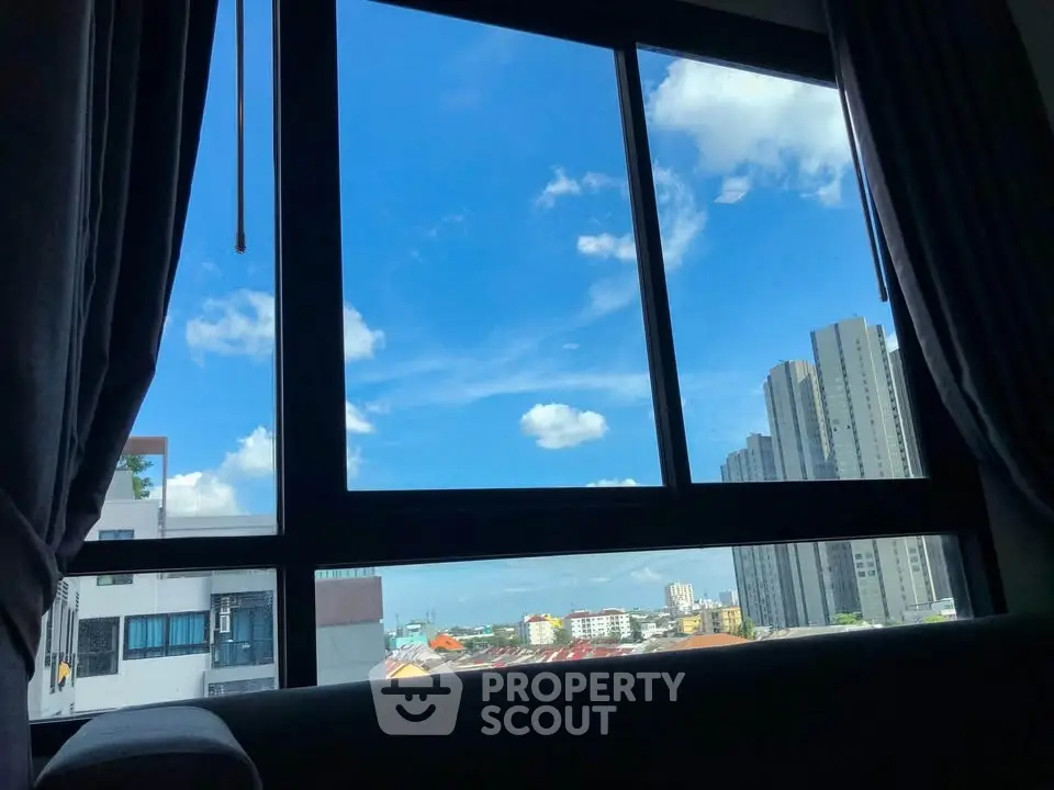 Stunning cityscape view from modern apartment window with blue sky and skyscrapers.