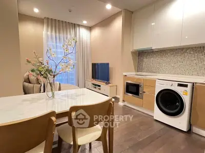 Modern living room with integrated kitchen featuring washing machine and microwave, elegant dining area, and cozy seating.