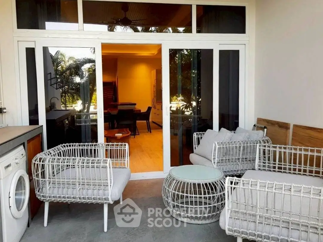 Chic patio with modern outdoor furniture and view into elegant dining area.