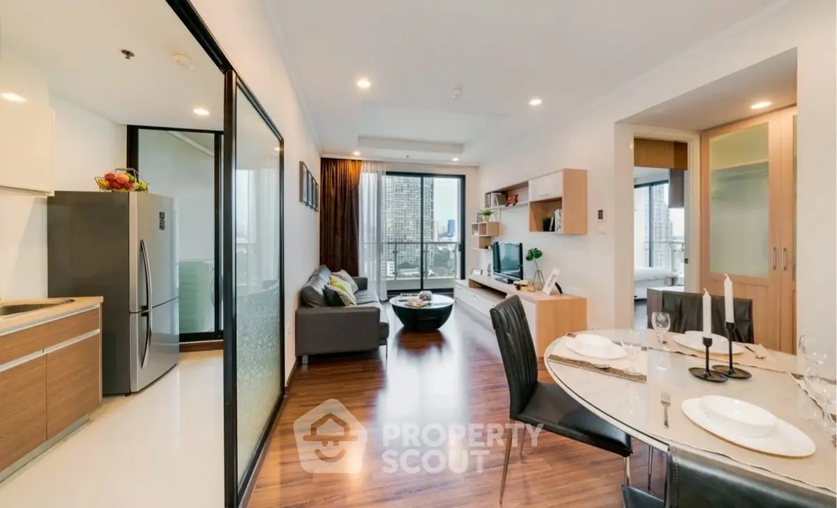 Modern open-plan living room with kitchen and city view, featuring elegant decor and natural light.