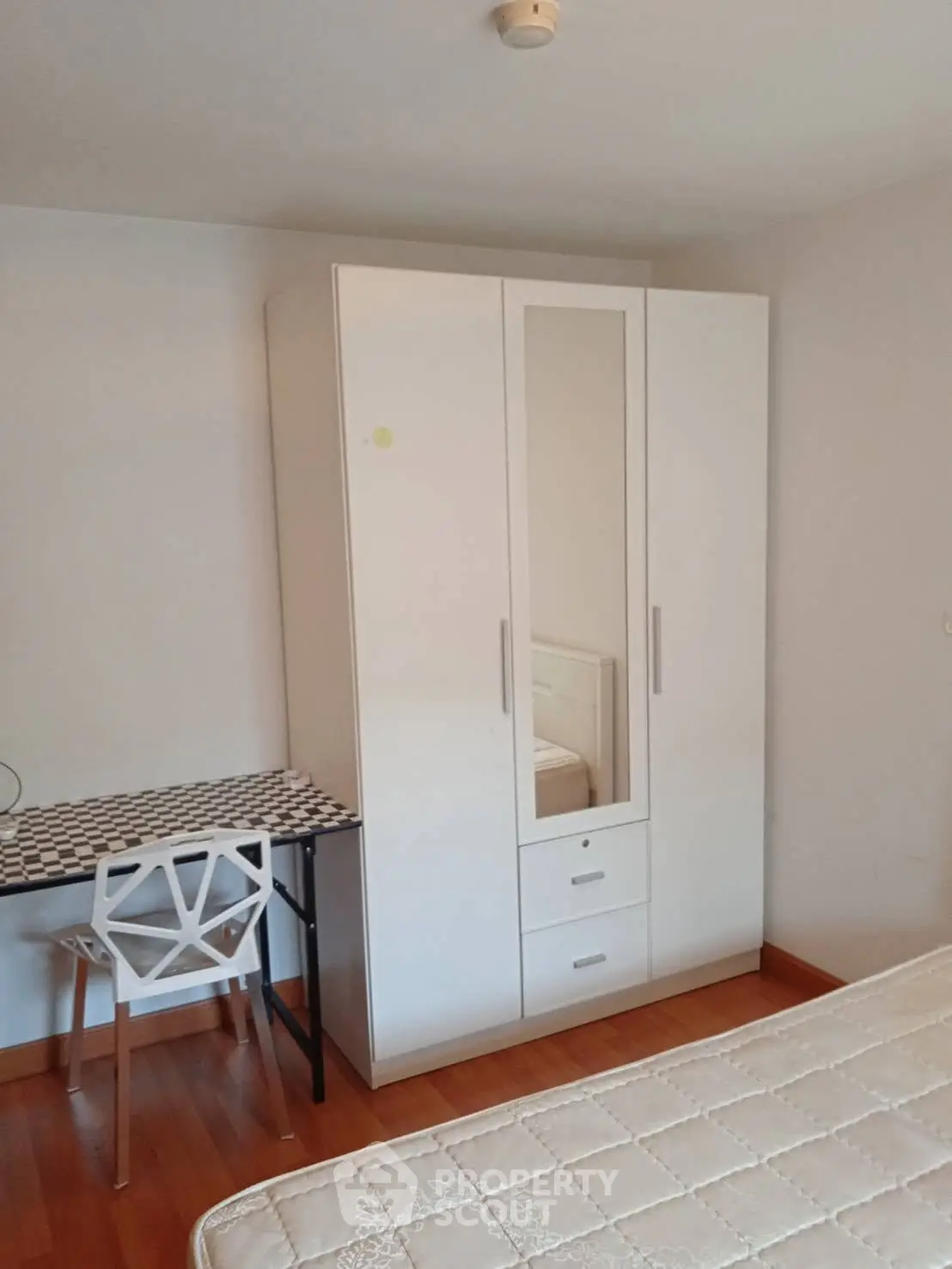 Cozy bedroom with modern wardrobe and stylish chair, perfect for comfortable living.