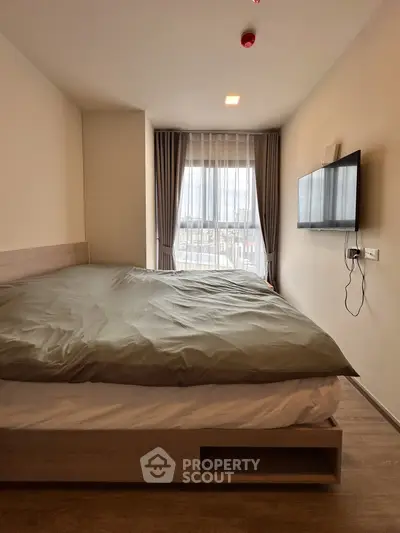 Modern bedroom with large window and wall-mounted TV, featuring a cozy bed and stylish decor.