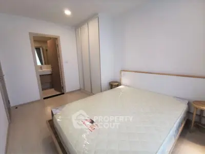 Spacious bedroom with a large bed and pristine flooring, leading to an en-suite bathroom, perfect for modern living.