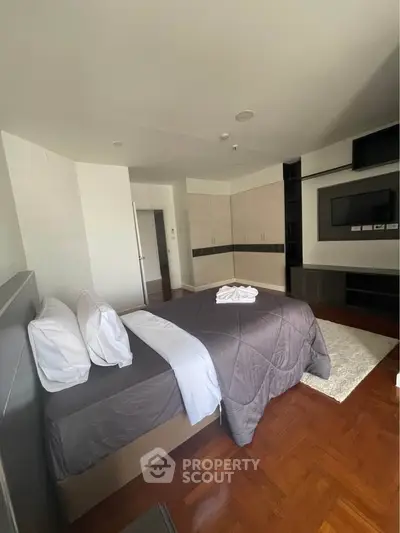 Spacious bedroom with modern furnishings and hardwood floors in a luxury apartment.