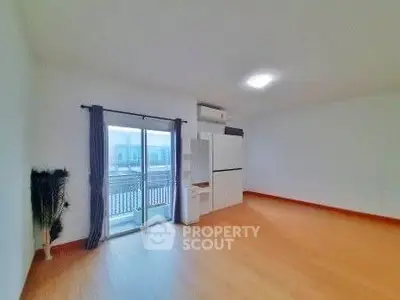 Spacious unfurnished living room with balcony access and wooden flooring.