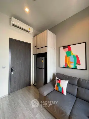 Modern living room with stylish decor and compact design, featuring a cozy sofa and contemporary artwork.