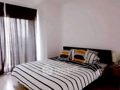 Cozy bedroom with stylish striped bedding and natural light from large window.