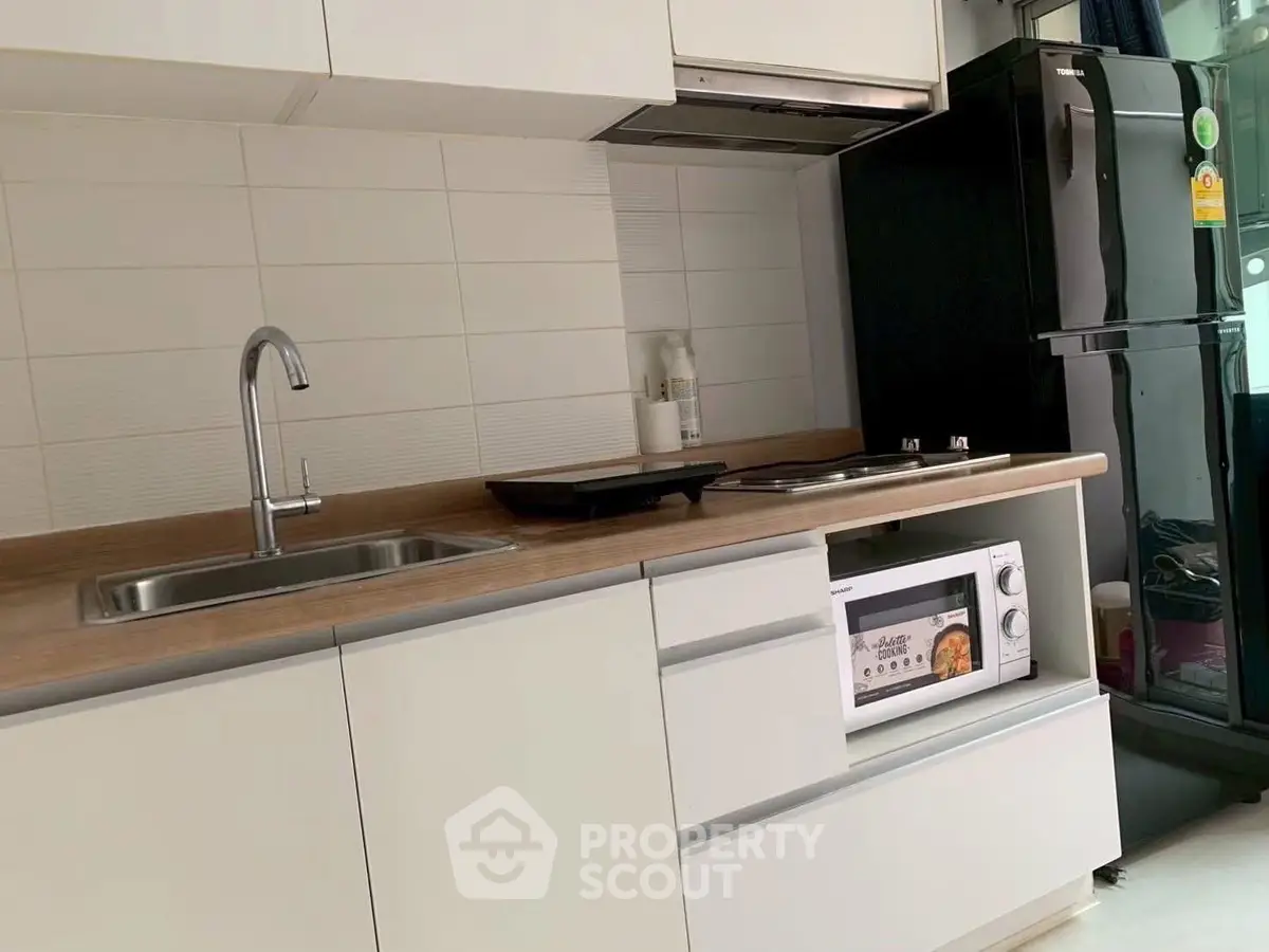 Modern kitchen with sleek white cabinets, built-in oven, and stainless steel sink.