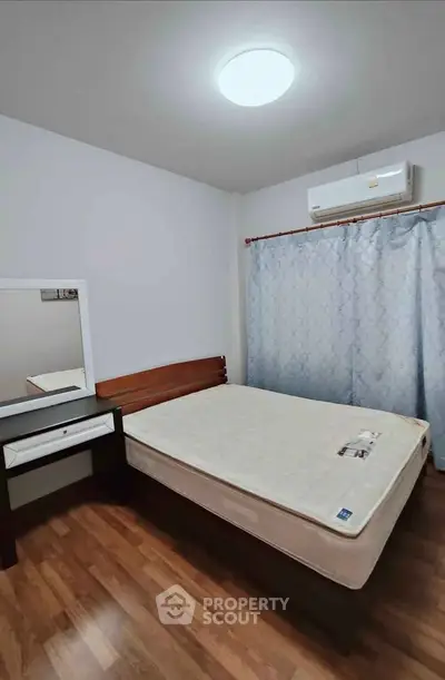 Cozy bedroom with wooden flooring, air conditioning, and a comfortable bed.
