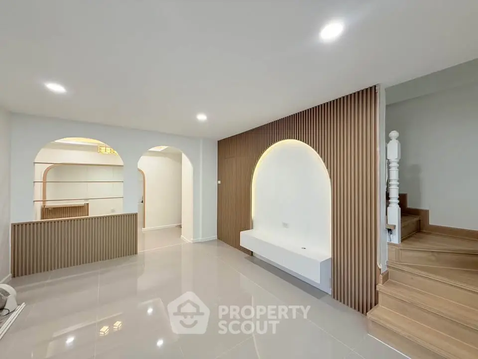 Modern interior with sleek design and wooden accents, featuring a stylish staircase and open layout.