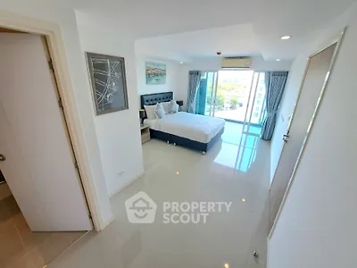 Spacious modern bedroom with large windows and balcony access, offering a bright and airy atmosphere.