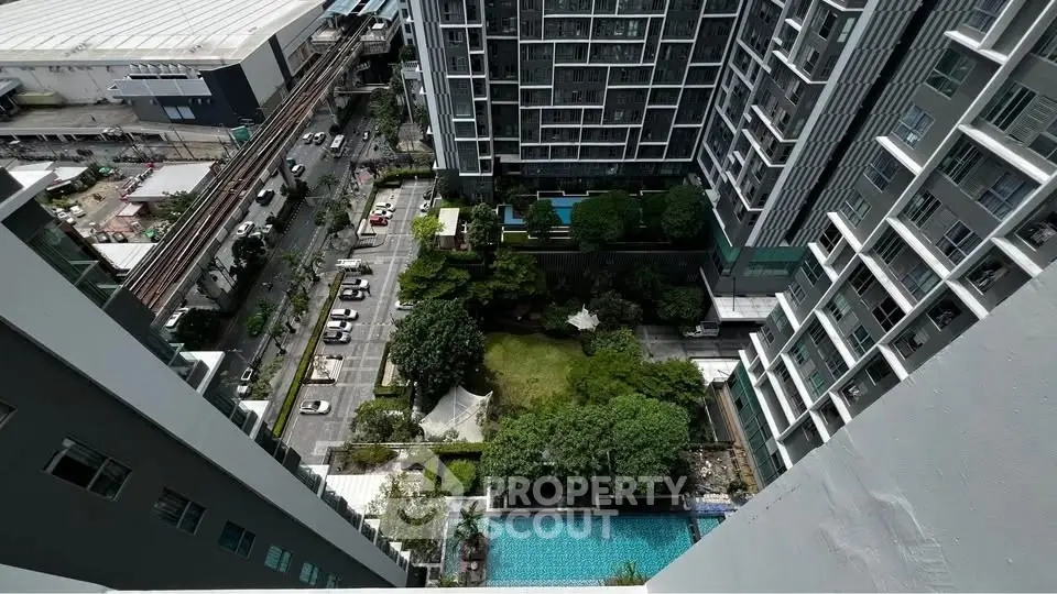 Stunning aerial view of modern high-rise building with lush garden and pool, perfect for urban living.