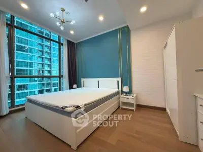 Modern bedroom with large windows and stylish blue accent wall in high-rise building.