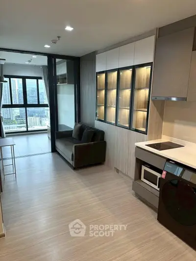 Modern open-layout kitchen and living area with city view, featuring sleek cabinetry and integrated appliances.