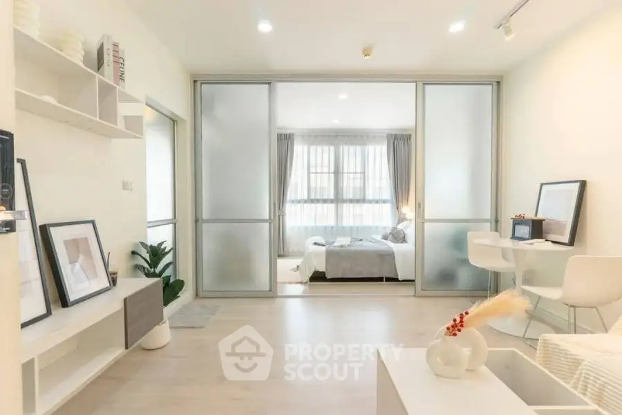 Modern open-plan living room with sliding doors leading to a bright bedroom
