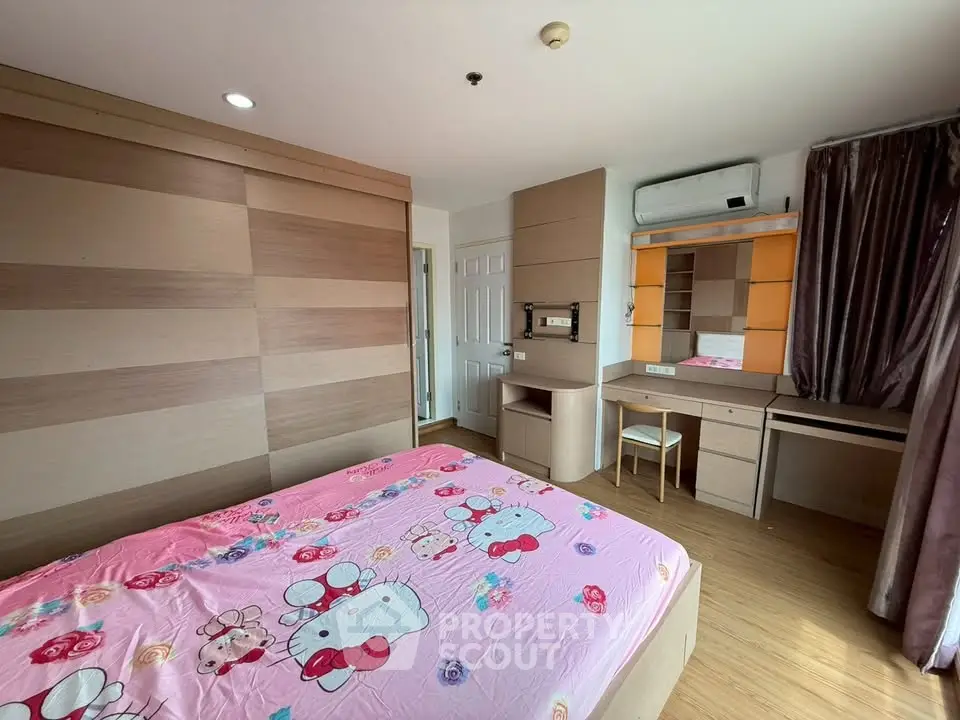 Cozy bedroom with wooden accents and built-in desk, featuring a playful pink bedspread.