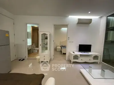 Modern living room with sleek furniture and open layout, featuring air conditioning and a flat-screen TV.