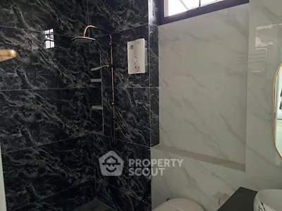 Modern bathroom with elegant black marble tiles and sleek shower design.