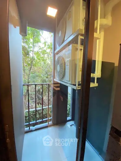 Compact balcony with air conditioning units and lush greenery view