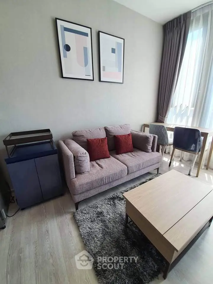 Modern living room with stylish decor, cozy sofa, and natural light from large window.