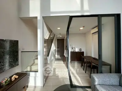 Modern living room with sliding glass doors and elegant dining area, featuring sleek furniture and abundant natural light.