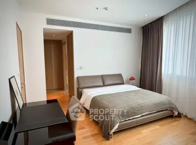 Spacious modern bedroom with elegant decor and natural light, featuring a comfortable bed and stylish furniture.