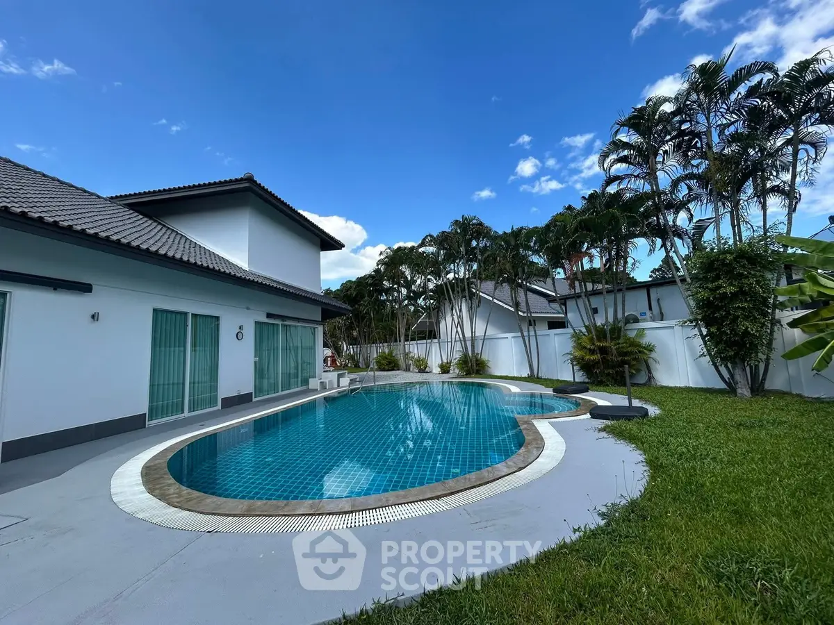 Luxurious villa with private pool and lush garden under clear blue sky