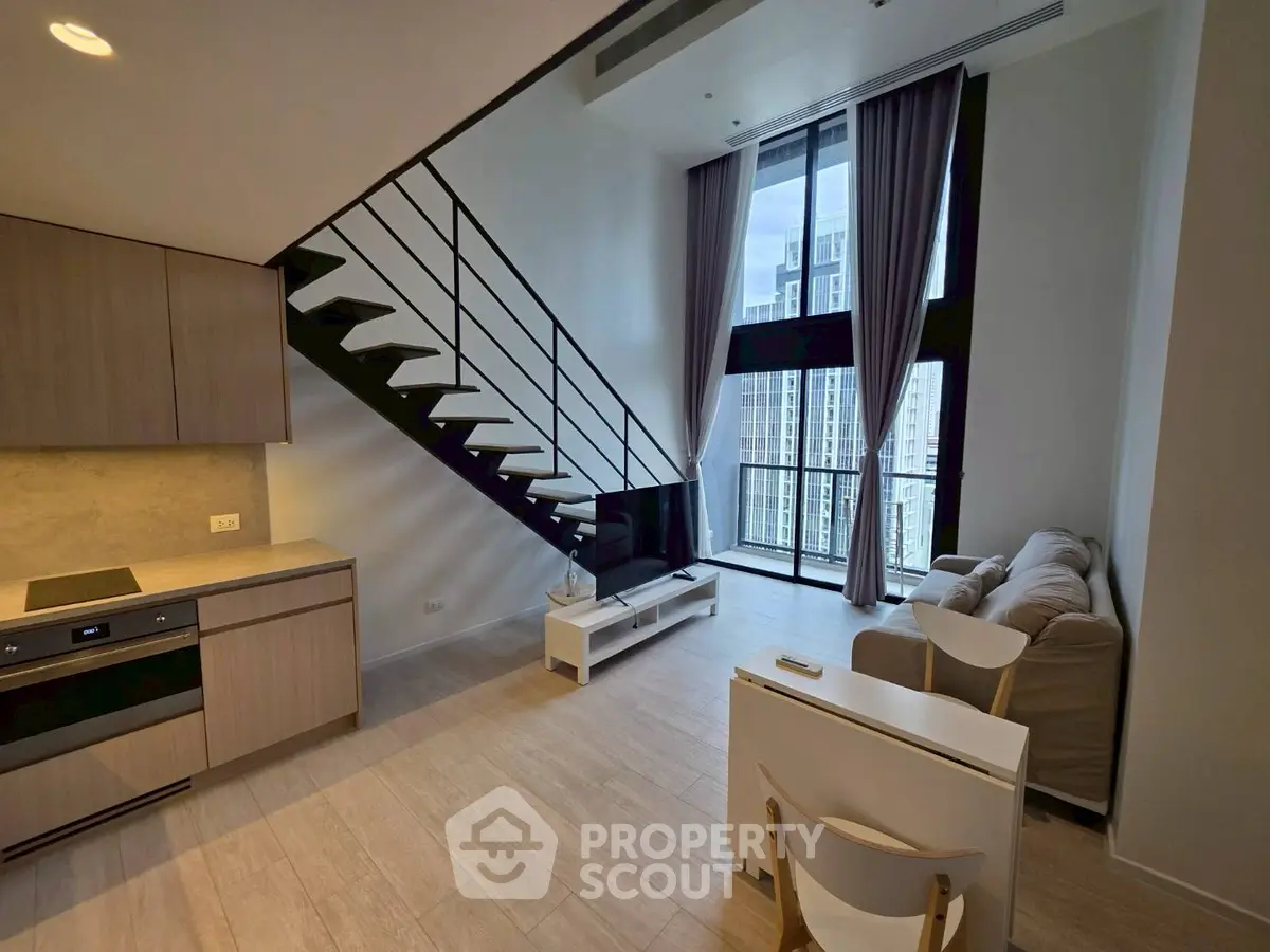 Modern loft apartment with high ceilings, open kitchen, and large windows offering city views.