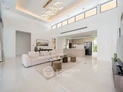 Luxurious open-plan living room with modern kitchen, high ceilings, and elegant lighting in a contemporary home.