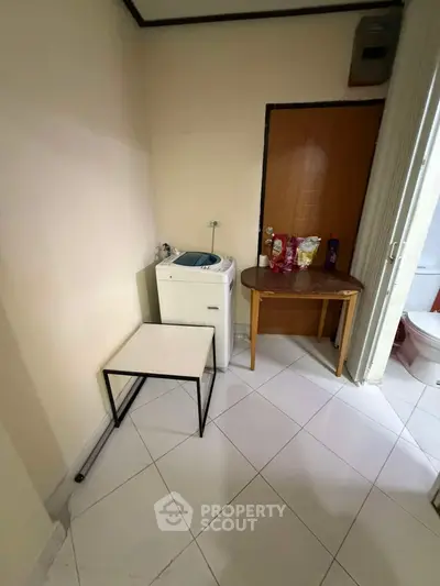 Compact laundry area with washing machine and small table in a cozy apartment corner.