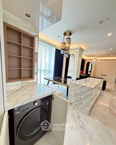 Luxurious open-plan kitchen with marble countertops and built-in washer in elegant apartment.