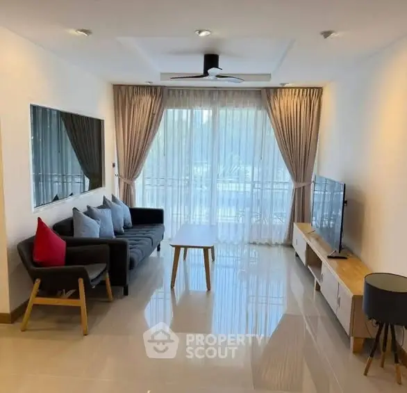 Modern living room with sleek furniture and large window offering natural light.