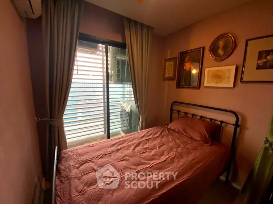 Cozy bedroom with single bed and art-decorated walls, featuring a window with city view.