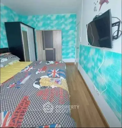 Vibrant bedroom with colorful bedding and wall-mounted TV, featuring modern wardrobe and wooden flooring.