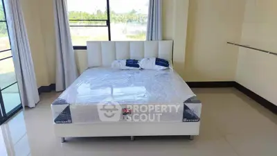 Spacious bedroom with large windows and modern bed, offering natural light and serene views.