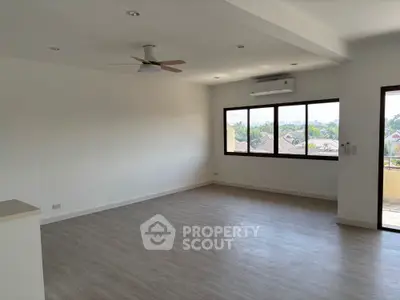 Spacious unfurnished living room with large windows and ceiling fan