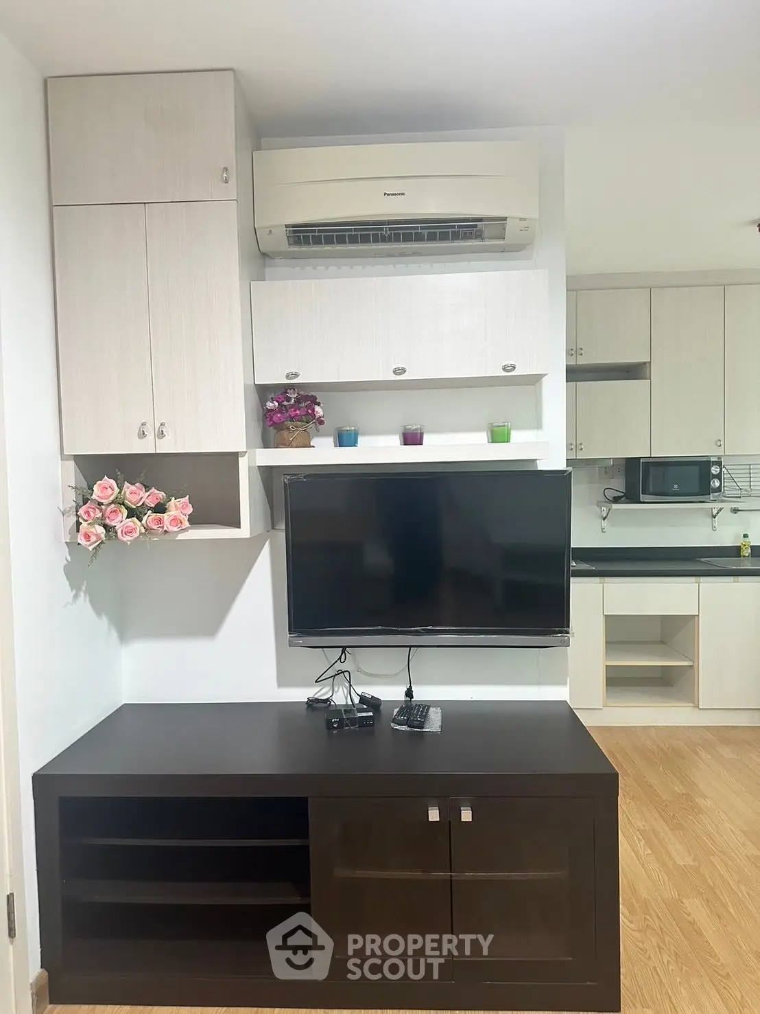 Modern living room with wall-mounted TV and stylish cabinetry, featuring air conditioning and elegant decor.