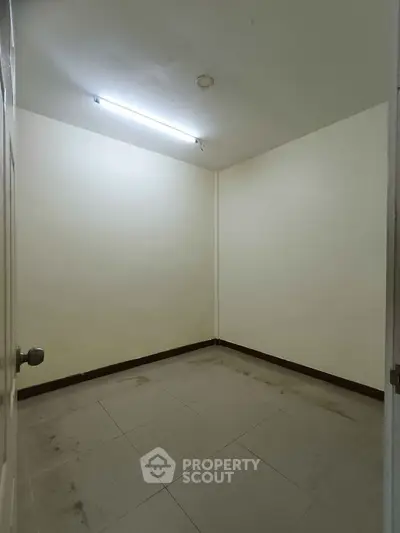 Minimalist empty room with tiled floor and fluorescent lighting, perfect for storage or small office space.