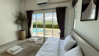 Luxurious bedroom with pool view, modern decor, and natural light, perfect for relaxation and comfort.