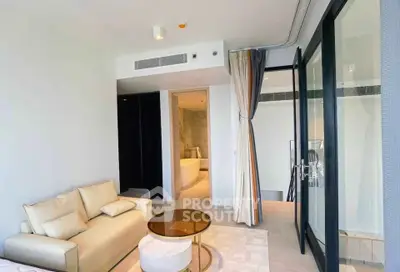 Modern living room with glass doors leading to a balcony, featuring a cozy sofa and elegant decor.