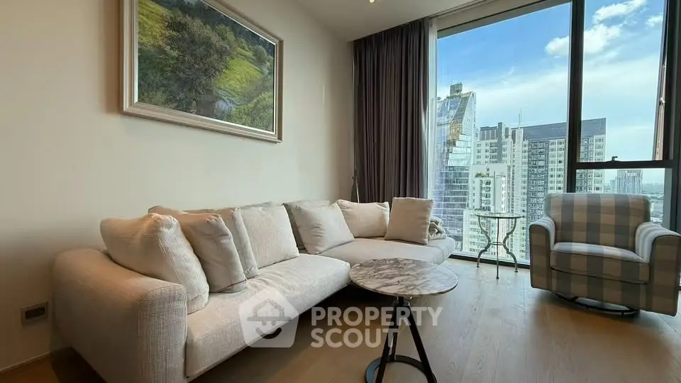 Modern living room with large windows and city view, featuring a cozy sofa and stylish armchair.